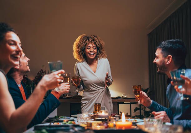 Group of happy friends talking and laughing around a dining table.