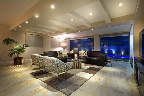 Luxurious living room with large windows, sofas, and armchairs.