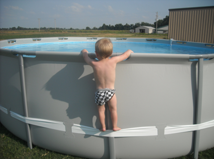 Child standing near an above-ground pool with visible pool straps and ladder, highlighting potential safety hazards