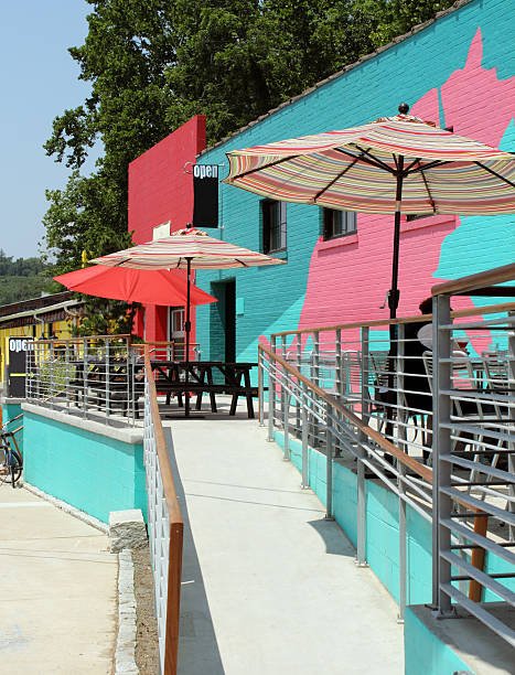A colorful cafe patio in Asheville, a city perfect for summer vacations with free local entertainment, featuring vibrant turquoise and pink walls and striped umbrellas on a sunny day.