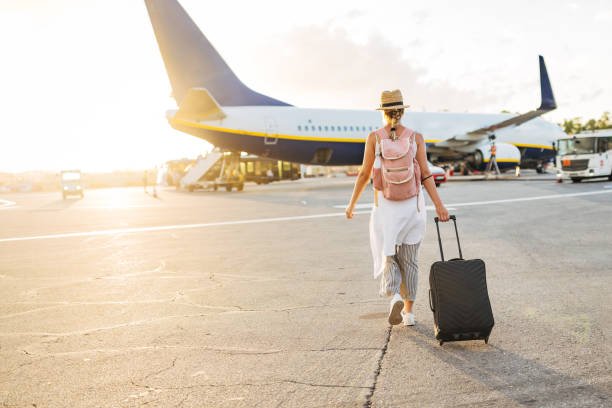 Woman with luggage walking towards a plane, ready to Explore Europe Cheap.