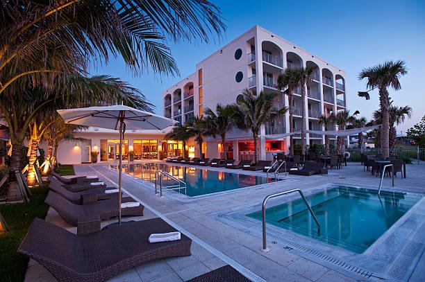 Beautiful Florida beach hotel at sunrise with swimming pool reflecting palm trees and golden sky