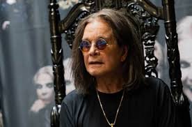 Person in black leather with sunglasses and rings, Ozzy Osbourne-inspired look.