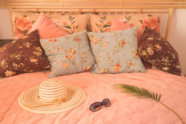 Summer-Bedding-Inspiration with elegant hat and sunglasses on a stylish bed in warm morning light.