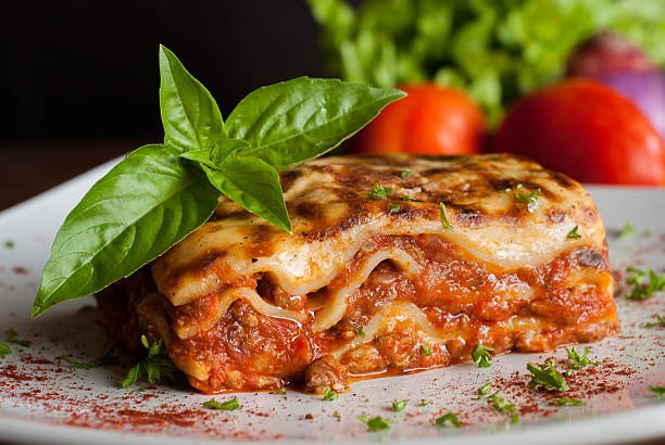 Lasagna on a square white plate with Italian basil 4. Lasagna or Baked Ziti Bonanza