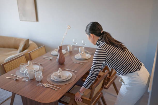 A woman carefully arranging chairs at a beautifully set table, a key step in her meticulous Dinner Party Planning.