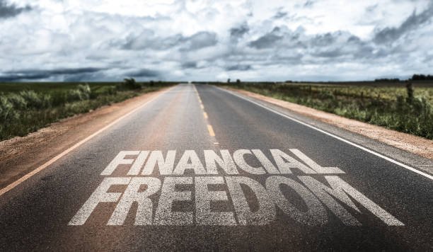 A long road stretches into the distance with the words "Tips for FINANCIAL FREEDOM" prominently written on the asphalt, symbolizing the journey towards it.