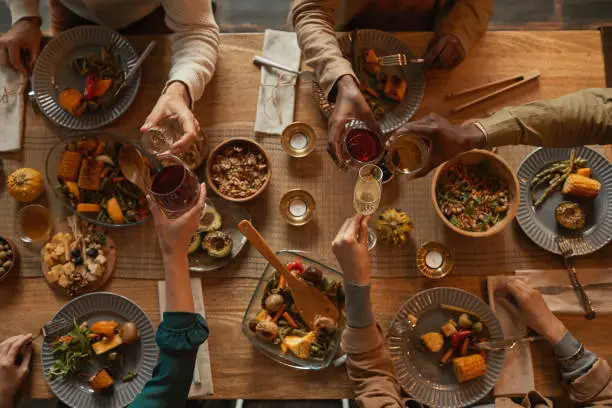 holiday meals An overhead view of a diverse group of friends or family toasting over a table filled with festive dishes, representing the joy of sharing creative Holiday Meal Ideas together.