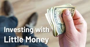 A hand holding a small stack of US dollar bills with the text "Investing with Little Money" overlaid, suggesting accessible investment options.