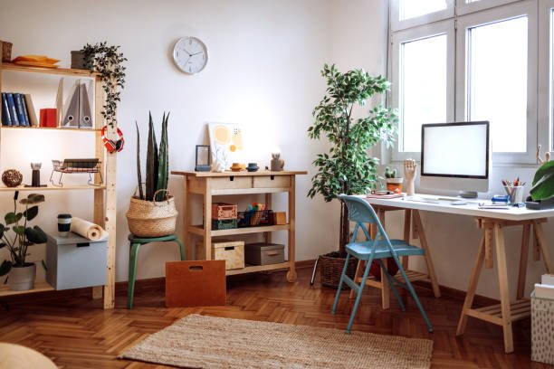 Cozy fall home office décor featuring a laptop and cup of tea on a desk bathed in warm sunset light from a nearby window, creating a serene and productive workspace, portraing affordable fall home office Décor