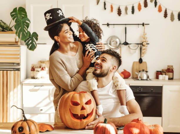 A happy family carving pumpkins together in their kitchen for Halloween.