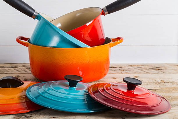 Colorful Le Creuset dupes, including yellow, red, white, and orange enameled cast iron Dutch ovens, displayed on a white surface.