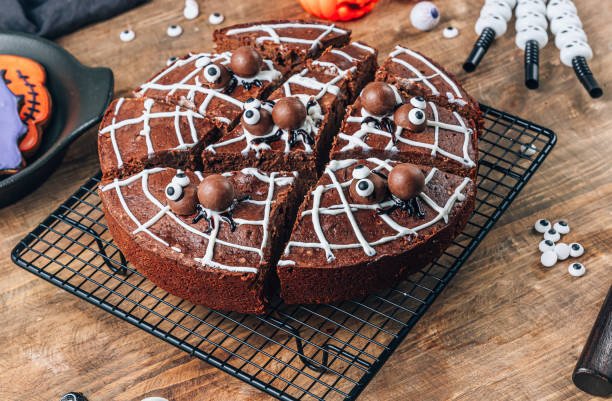 Spooky spiderweb brownies, a delicious and cheap Halloween party ideas, on a wire cooling rack with candy eyeballs and other Halloween decor.