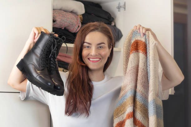 An woman is organizing the cloths in wardrobe, showcasing fall wardrobe organization.