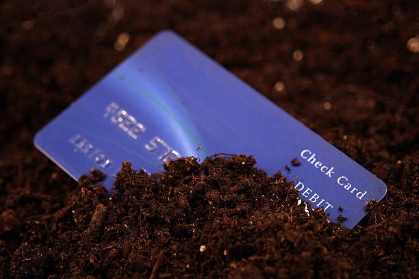 a credit card partially buried in dirt with a narrow depth of field.